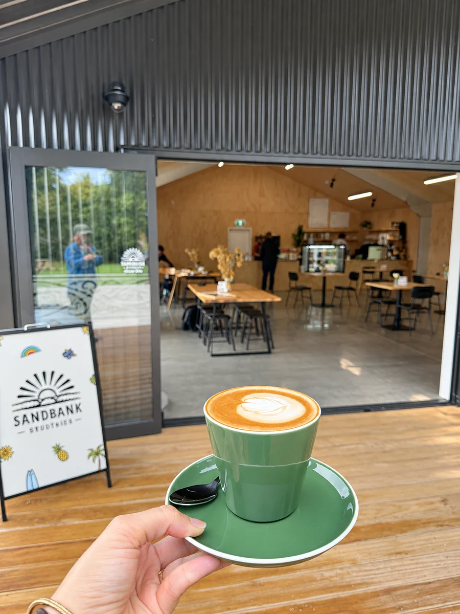 A green takeaway coffee cup outside Omanawa Cafe