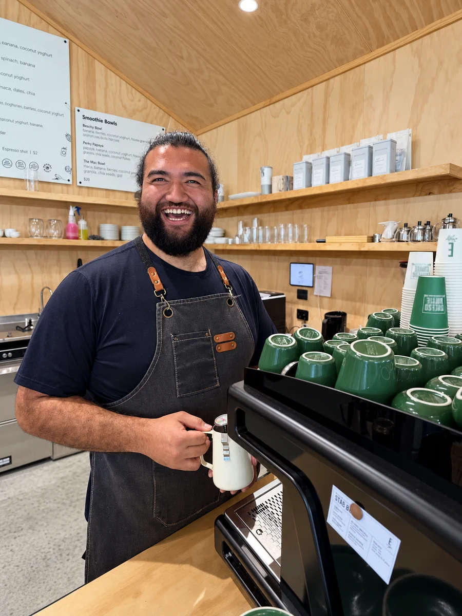A smiling barista at the Omanawa Cafe coffee machine